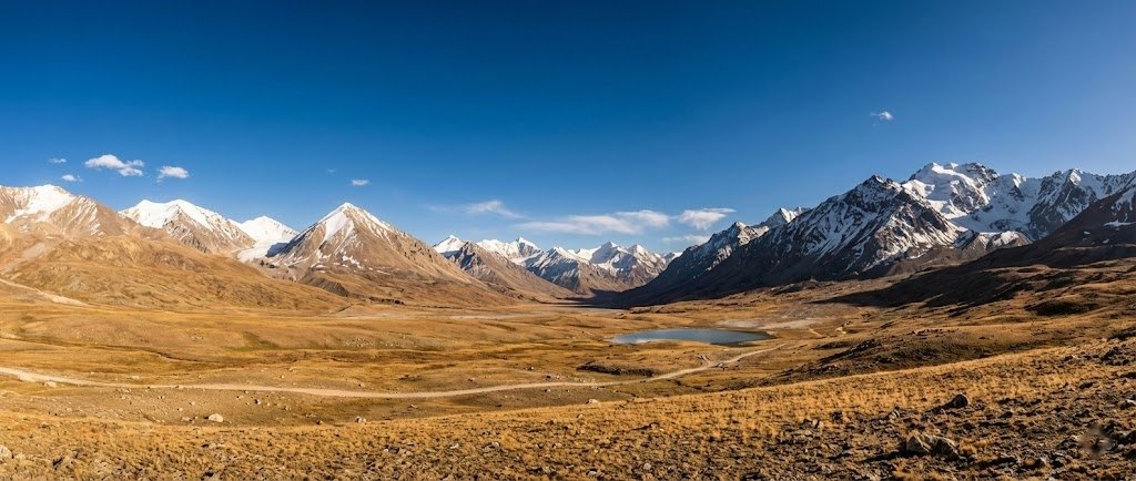 Panoramic view of Shimshal Pass at 4,735m, vast Pamir plateau surrounded by snow-capped Karakoram peaks, Pakistan