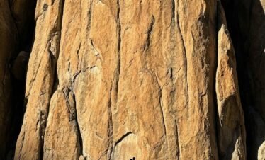 Towering vertical granite rock face in Nangma Valley Skardu Pakistan, known as the Yosemite of the Karakoram, trekker at base for scale
