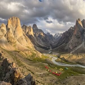 Panoramic ridge view of the entire Nangma Valley below with dramatic granite towers on both sides and expedition tents visible on the valley floor, Skardu Pakistan