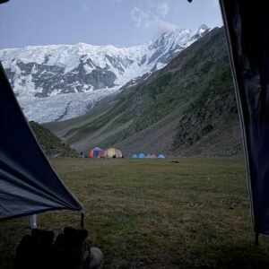 View from inside a tent at Rakaposhi Base Camp looking across the campsite to the towering snow-capped Rakaposhi peak, northern Pakistan