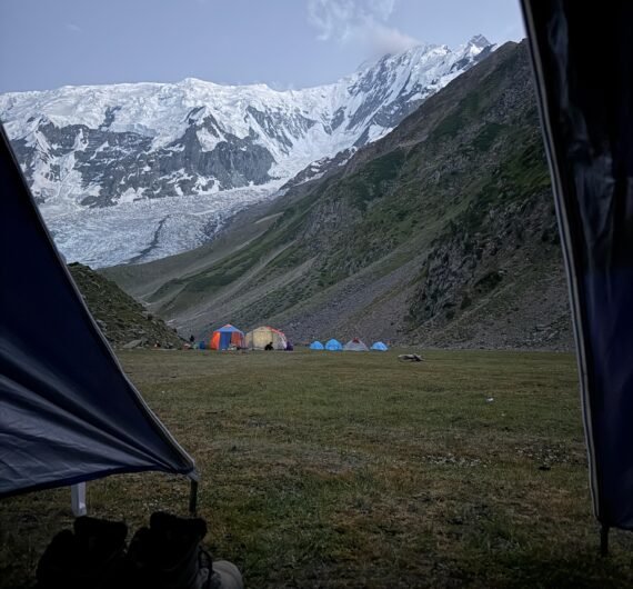 View from inside a tent at Rakaposhi Base Camp looking across the campsite to the towering snow-capped Rakaposhi peak, northern Pakistan