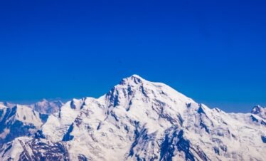Aerial view of Rakaposhi summit at 7,788m rising above the Karakoram range against a deep blue sky, northern Pakistan