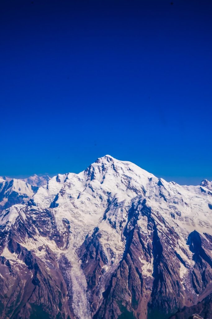 Aerial view of Rakaposhi summit at 7,788m rising above the Karakoram range against a deep blue sky, northern Pakistan