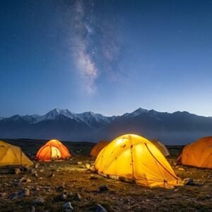 Expedition tents pitched on the Shimshal Pamir plateau at dusk with the Milky Way above snow-capped peaks, high altitude trekking Pakistan