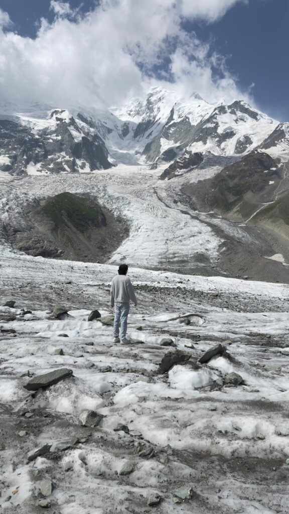 Trekker standing on the Rakaposhi glacier with the massive 7,788m Rakaposhi summit towering behind, northern Pakistan