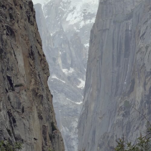 Misty Granite Gorge, Nangma Valley, Karakoram Range, Pakistan Description: Cloud and mist drift through a narrow granite gorge in Nangma Valley, Skardu district, Gilgit-Baltistan, revealing snow-covered peaks of the Karakoram range beyond the towering rock walls.